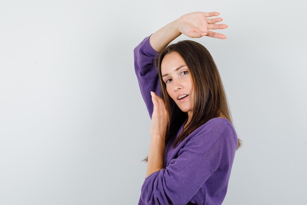 Young female posing while looking at camera in violet shirt and looking cute. .