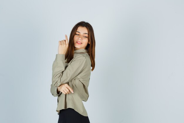 Young female posing while looking over her shoulder in shirt