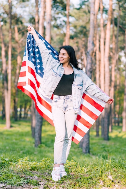 Free photo young female posing with american flag in park