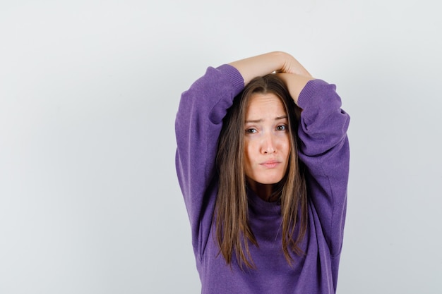 Free photo young female posing with crossed arms on head in violet shirt and looking confident , front view.