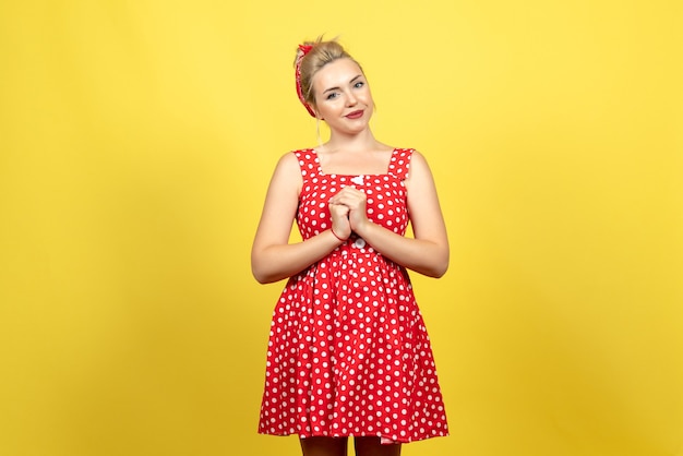 Free photo young female in red polka dot dress just standing on yellow