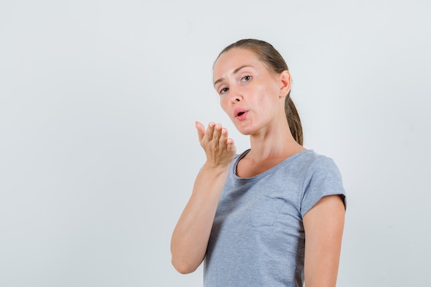 Free Photo young female sending air kiss in grey t-shirt , front view.