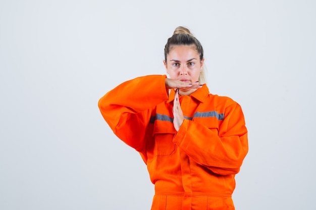 Free Photo young female showing break time gesture in worker uniform and looking strict. front view.