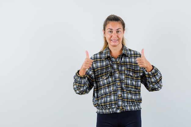 Free photo young female showing double thumbs up in shirt, shorts and looking confident , front view.