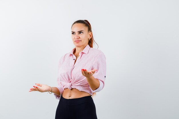 Young female showing helpless gesture in casual shirt and looking stressed