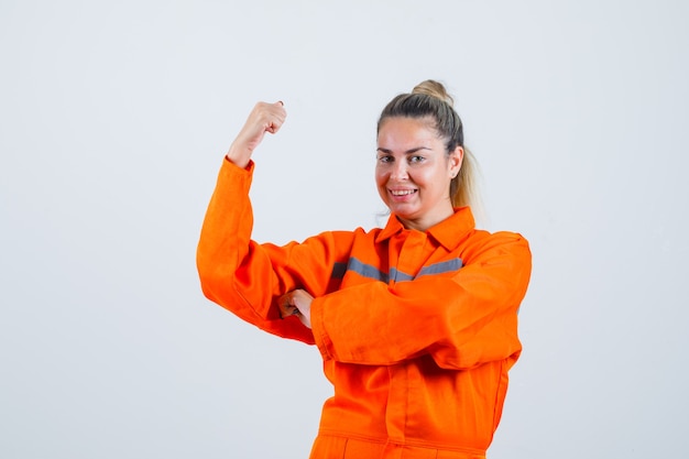 Free photo young female showing her arm power in worker uniform and looking ready. front view.