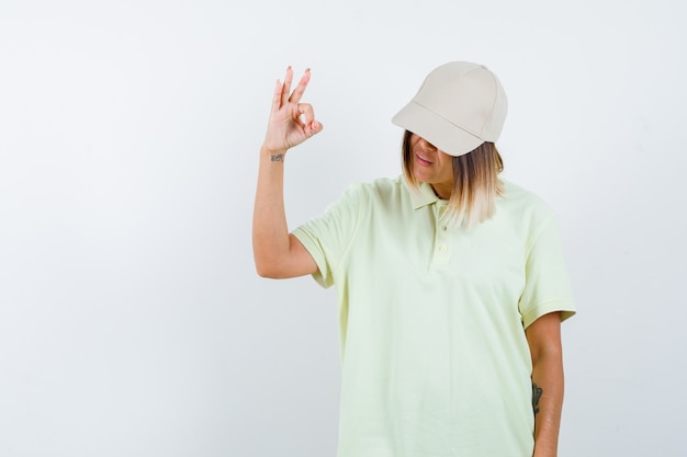 Free photo young female showing ok gesture in t-shirt, cap and looking confident. front view.