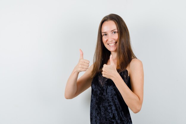 Young female showing thumbs up in black singlet and looking pleased