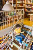 Free photo young female sitting on stairs with book