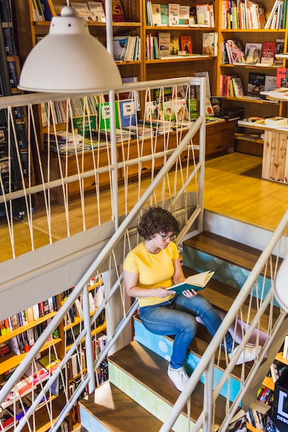 Free Photo young female sitting on stairs with book