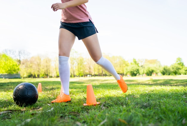 Young female soccer player practicing on field