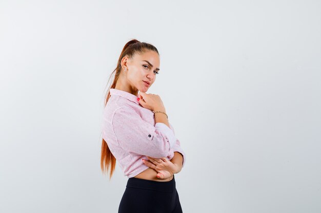 Young female standing in thinking pose in casual shirt and looking confident , front view.