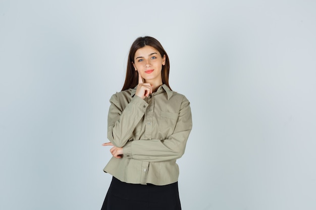 Young female standing in thinking pose in shirt, skirt and looking confident