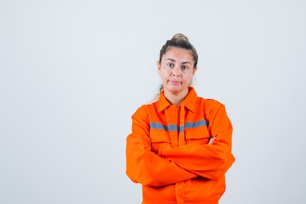 Free photo young female standing with crossed arms in worker uniform and looking hesitant. front view.