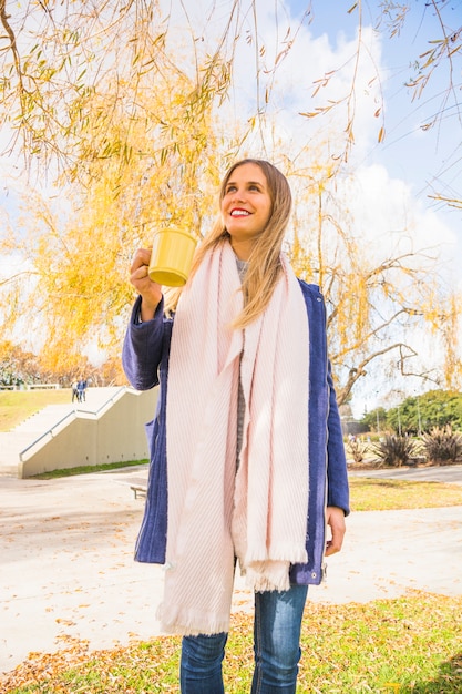 Young female standing with tea cup in autumn park