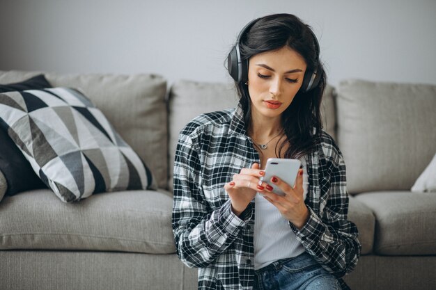 Young female student listening music through phone on earphones