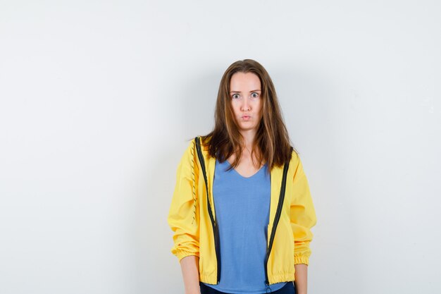 Young female in t-shirt, jacket looking at camera and looking puzzled , front view.