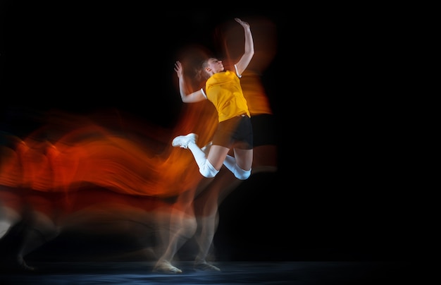 Young female volleyball player on black studio in mixed light.