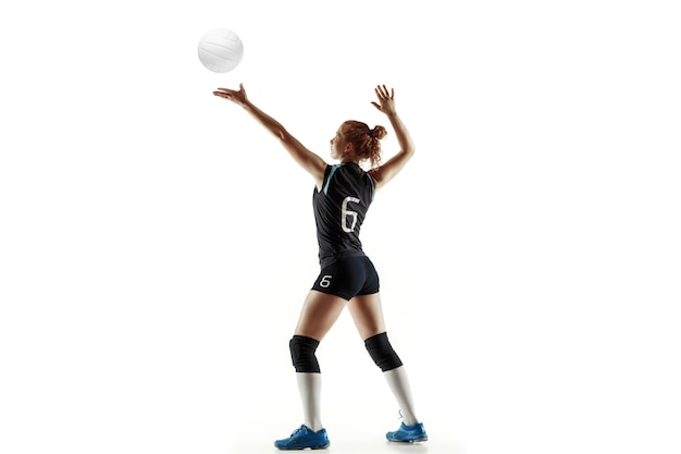 Young female volleyball player isolated on white studio background. Woman in sport's equipment and shoes or sneakers training and practicing. Concept of sport, healthy lifestyle, motion and movement.