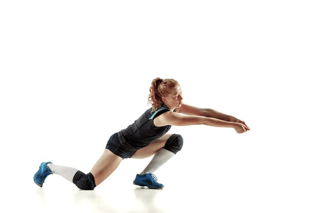 Young female volleyball player isolated on white wall. Woman in sport's equipment and shoes or sneakers training and practicing. Concept of sport, healthy lifestyle, motion and movement.