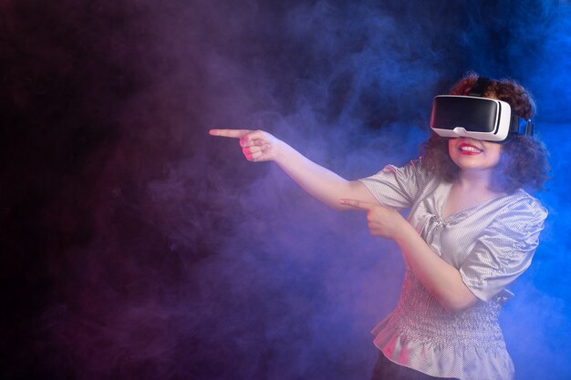 Young female wearing virtual reality headset on dark blue surface