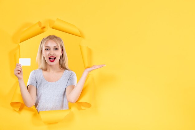 Young female with credit card on yellow background facial money sale shopping