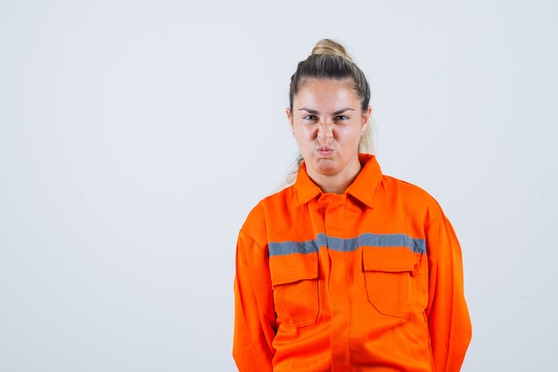 Free photo young female in worker uniform looking while pouting her lips and looking weird , front view.