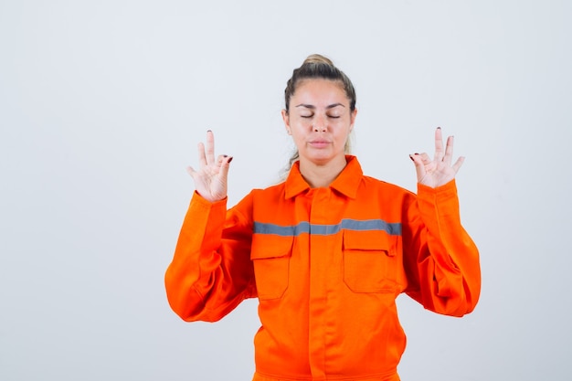 Free photo young female in worker uniform meditating and looking silent , front view.