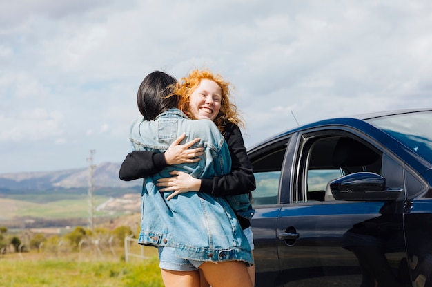 Free photo young females hugging on roadside