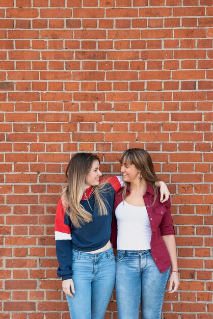 Young females posing together with brick wall