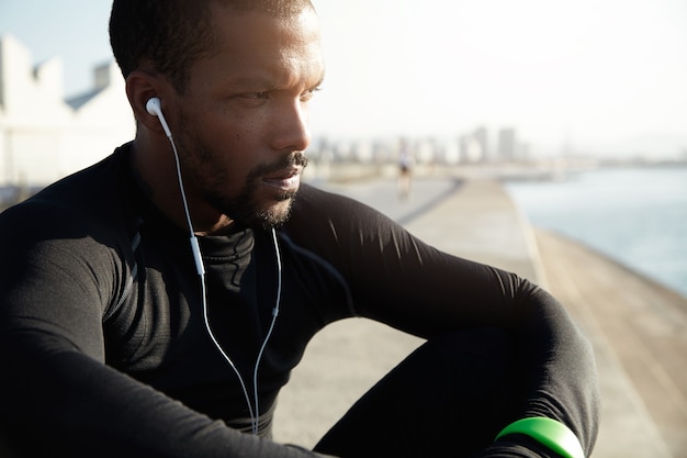 Young fit man at the beach listening to music