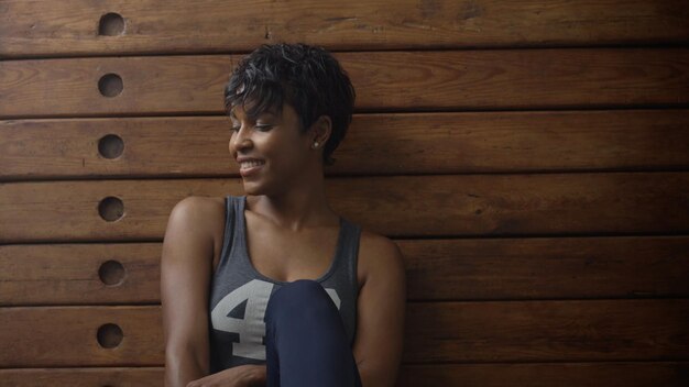 Free Photo young fit and tone up woman sits lean on wooden wardrobe during workout rest in loft