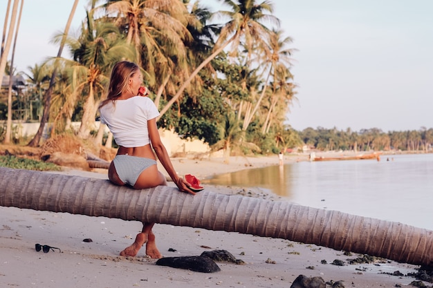 Free photo young fit woman with watermelon on tropical beach at sunset