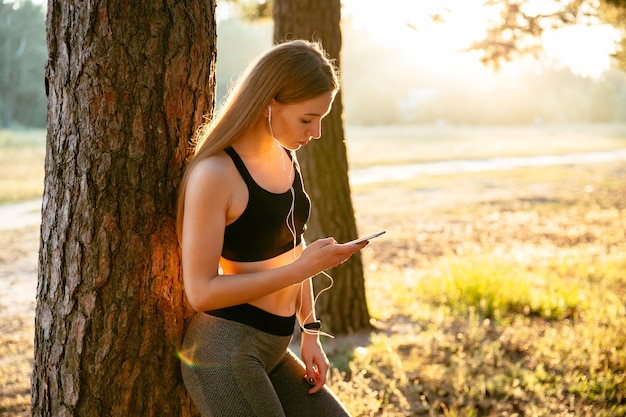 Free Photo young fitness girl listening to music in earphones and using a smartphone