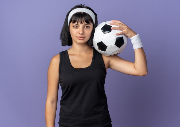 Young fitness girl wearing headband looking at camera with serious confident expression 