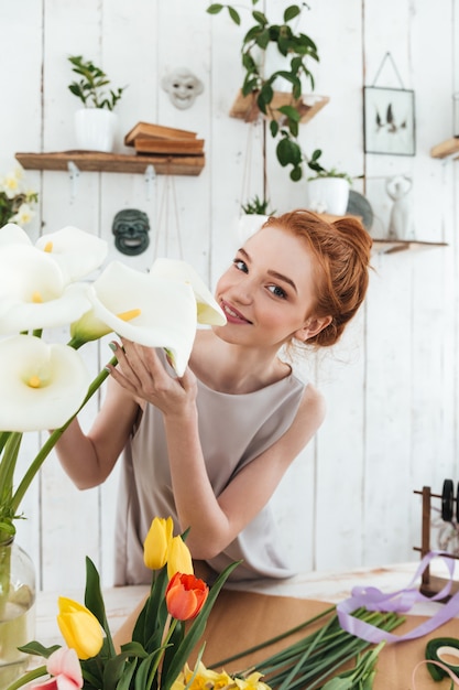 Free photo young florist smelling white flowers while working