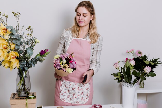 Young florist standing with arranged bouquet