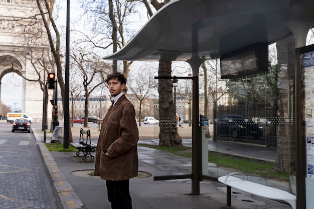 Free photo young french man waiting at the station for the bus