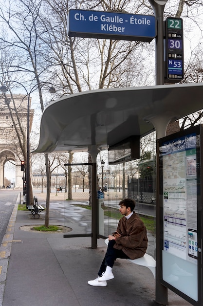 Free photo young french man waiting at the station for the bus