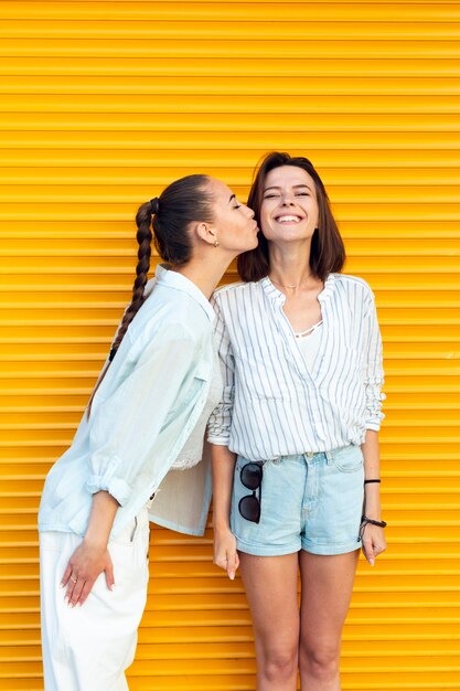 Young friends kissing her friend on the cheek 