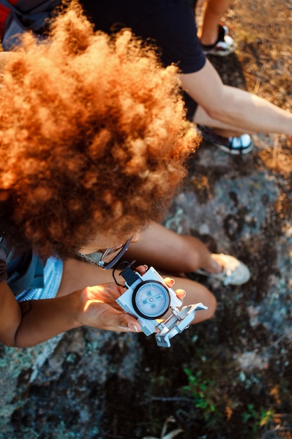 Free photo young friends sitting on rock in canyon, looking at compass