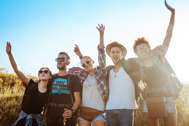 Young friends smiling, rejoicing, looking at camera, standing in field