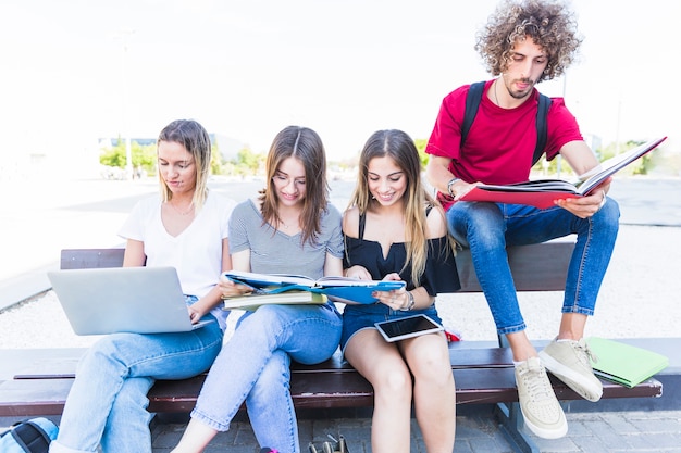 Young friends studying on bench