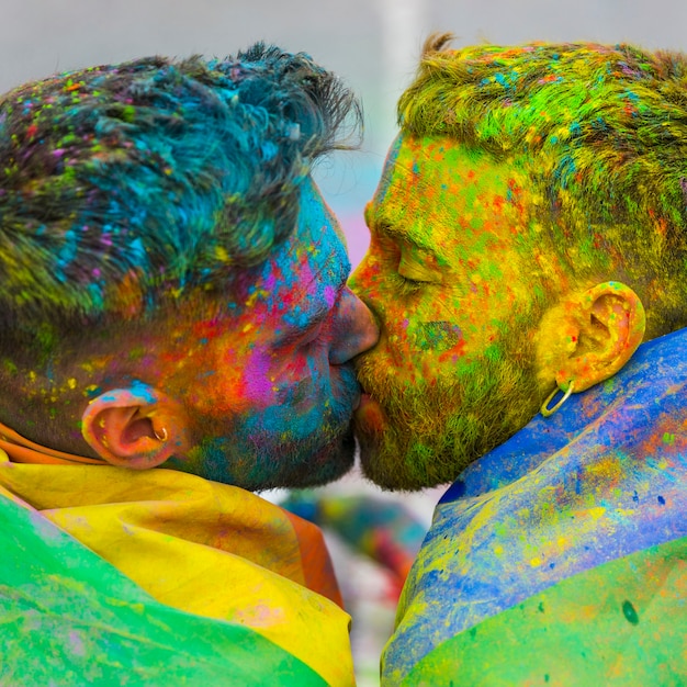 Young gays kissing on Holi color festival