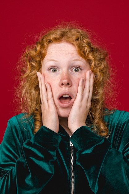 Free photo young ginger shocked woman holding cheeks