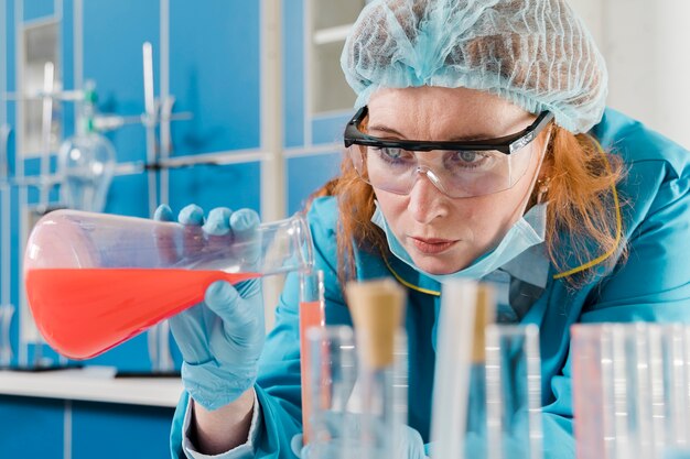 Young ginger woman chemist mixing the liquids