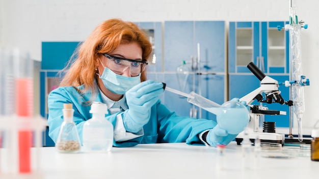 Free photo young ginger woman chemist working in her lab