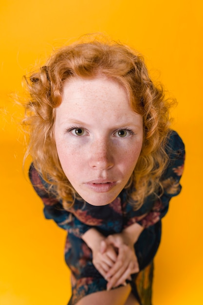 Young ginger woman looking straightly at camera attentively