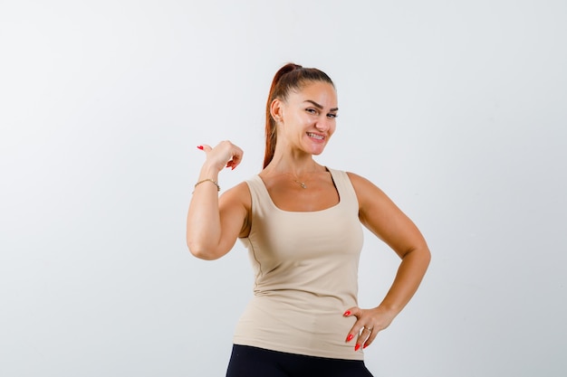 Young girl in beige top, black pants holding one hand on waist