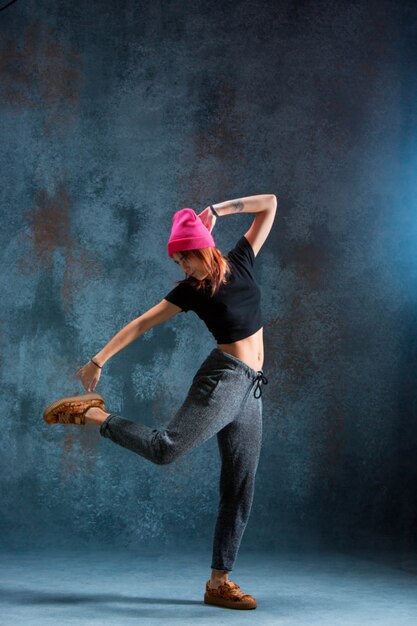 Young girl break dancing on wall background.